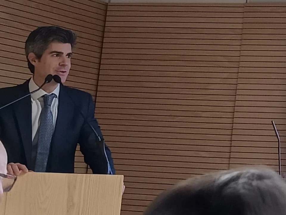 El Dr. Pérez-Carral, de perfil y con micrófono, durante su charla ante un atril