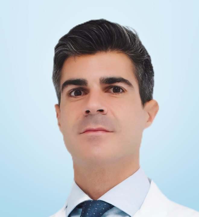 Dr. José Ramón Pérez-Carral, urólogo, con bata blanca, camisa azul clara y corbata