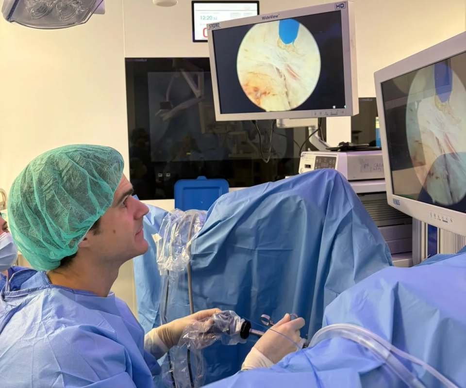 El Dr. Pérez-Carral en quirófano, con gorro verde y bata azul, observando el monitor del endoscopio