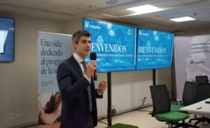 El Dr. Pérez-Carral habla ante las pantallas de bienvenida del Curso Internacional de Enucleación Prostática Avanzada HoLEP · ThufLEP en Cancún
